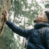 Man in Blue Bubble Jacket Standing Beside Tree